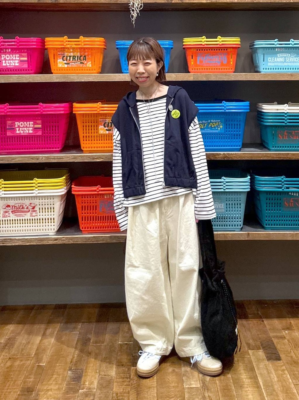 ベージュ系のスニーカー、ホワイト系のTシャツ/カットソー、ブルー系のベストを着用したレディースの春コーディネートの1枚目の写真