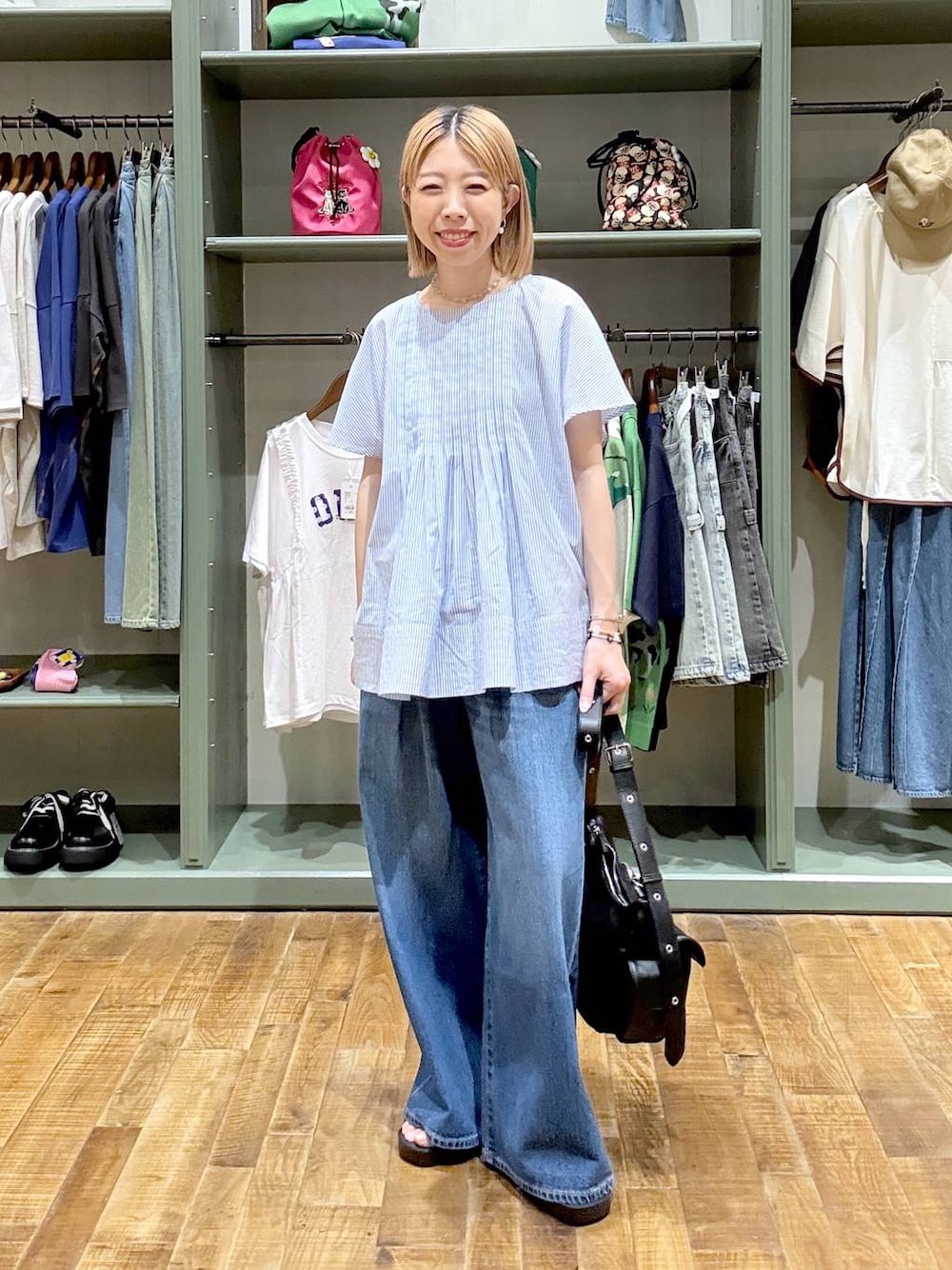 ブラック系のショルダーバッグ、ブルー系のデニムパンツ、ブラック系のサンダルを着用したレディースの夏コーディネートの1枚目の写真