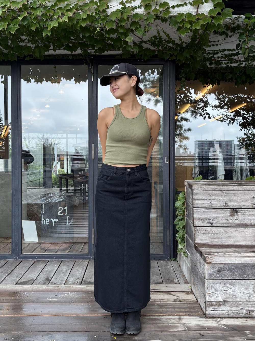 グリーン系のタンクトップ、ブラック系のデニムスカートを着用したレディースの秋コーディネートの1枚目の写真