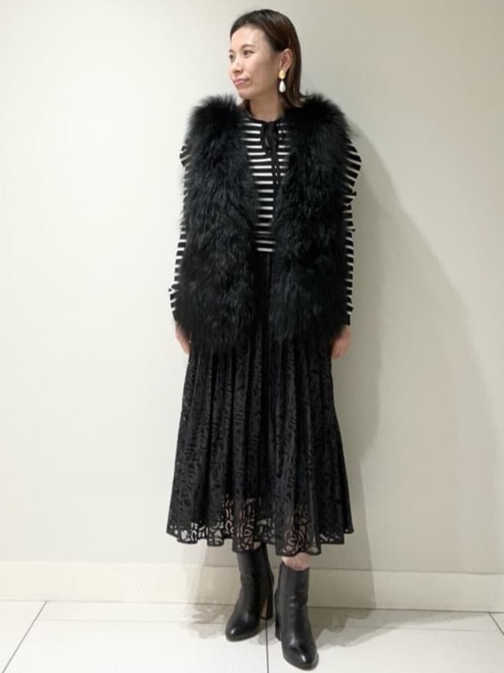 ホワイト系のニット/セーター、ブラック系のスカート、ブラック系のムートンコートを着用したレディースの冬コーディネートの1枚目の写真