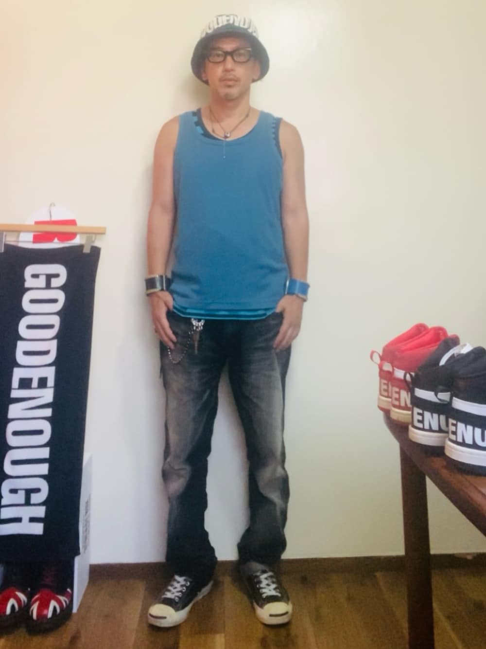 ブルー系のタンクトップ、ブラック系のデニムパンツ、ブラック系のスニーカーを着用したメンズの夏コーディネートの1枚目の写真
