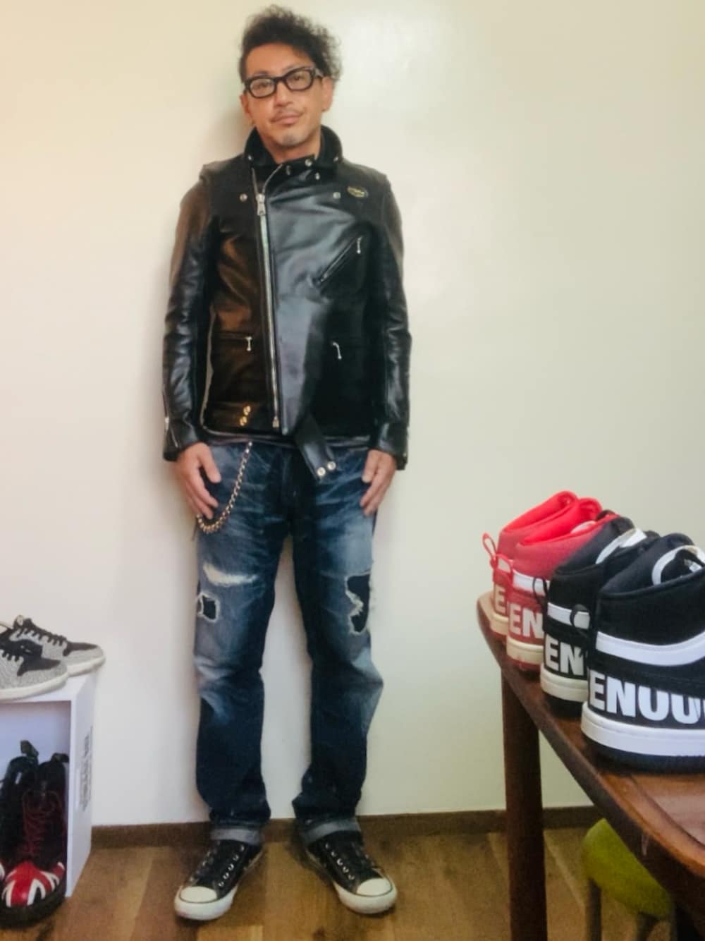 ブラック系のライダースジャケット、ブルー系のデニムパンツ、ブラック系のスニーカーを着用したメンズの秋コーディネートの1枚目の写真