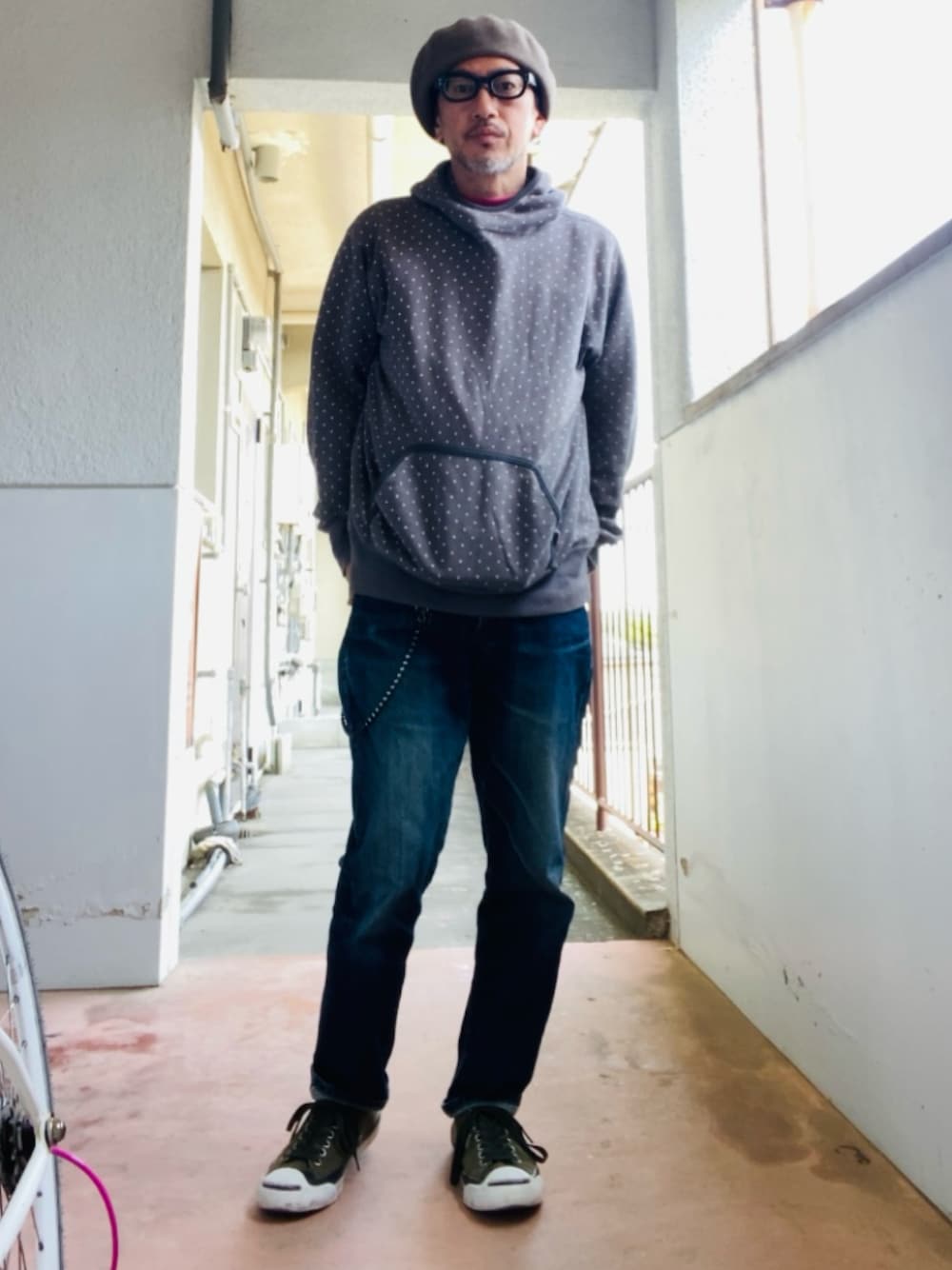 グレー系のパーカー、ブルー系のデニムパンツ、グリーン系のスニーカーを着用したメンズの春コーディネートの1枚目の写真