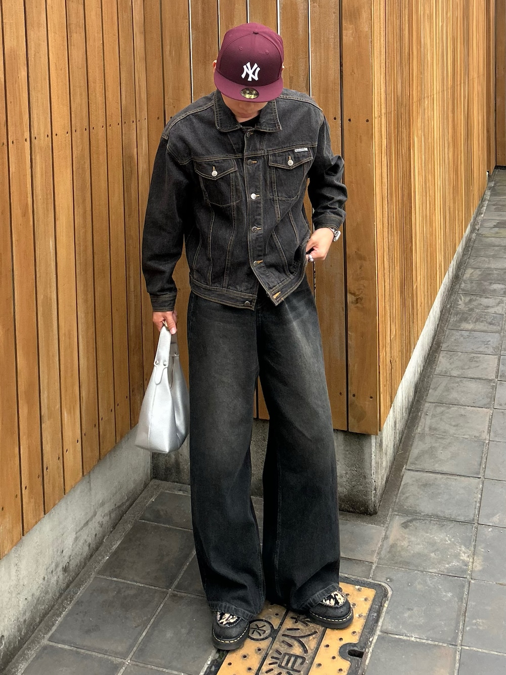 ブラック系のデニムジャケット、シルバー系のハンドバッグ、ブラック系のローファーを着用したメンズの春コーディネートの1枚目の写真