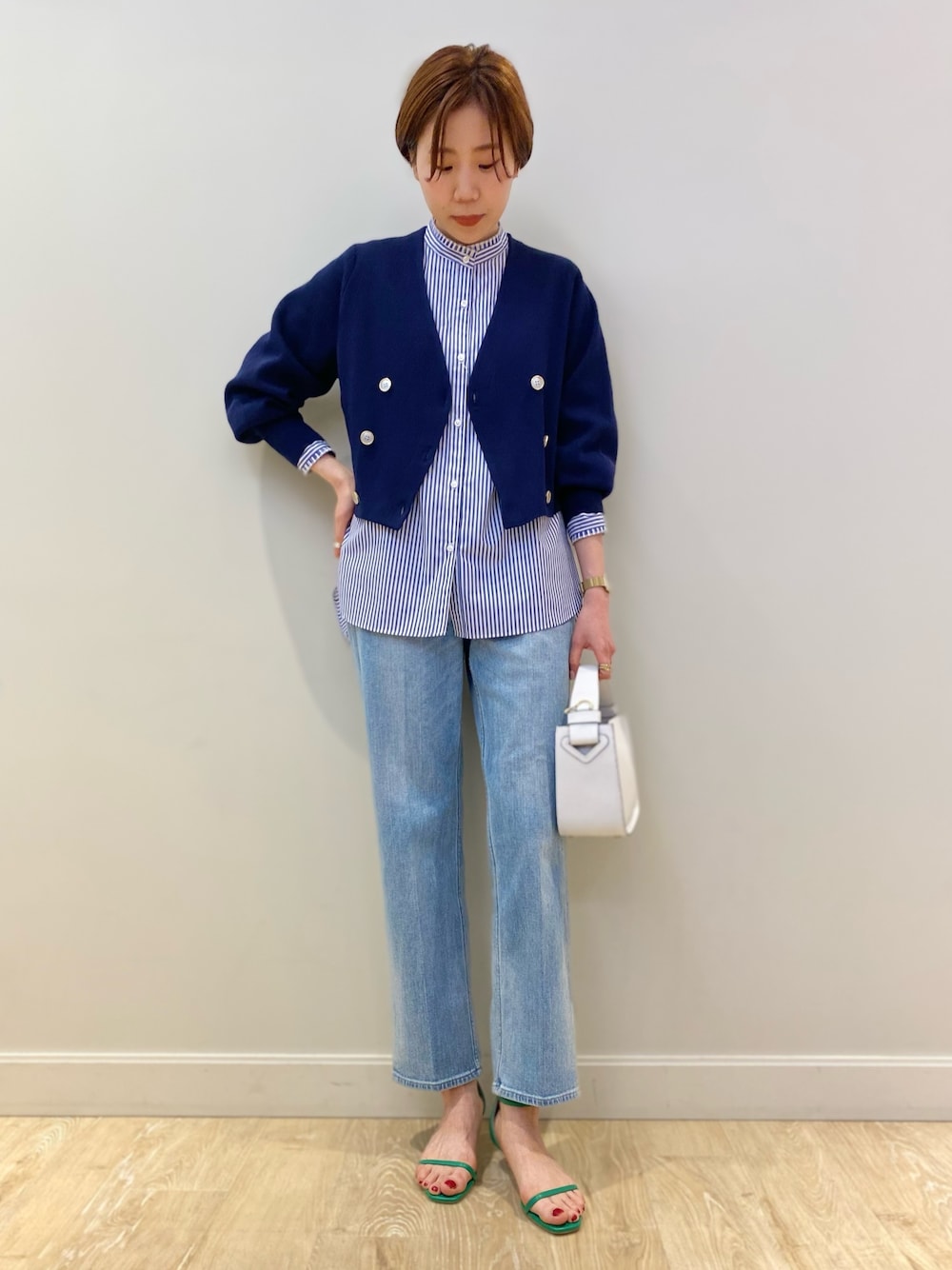 ホワイト系のショルダーバッグ、ブルー系のカーディガン/ボレロ、ブルー系のシャツ/ブラウスを着用したレディースの冬コーディネートの1枚目の写真