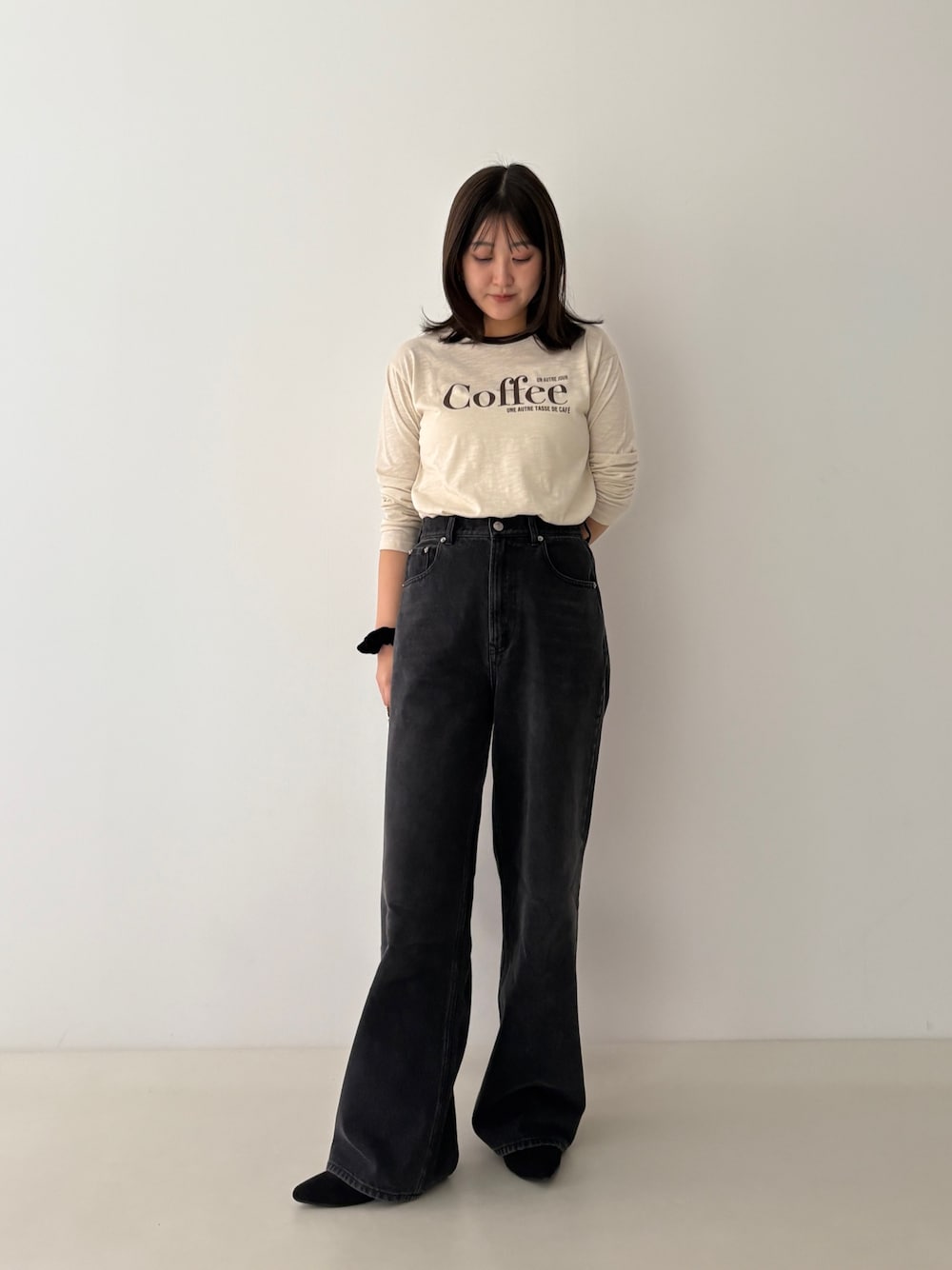 ベージュ系のTシャツ/カットソー、ブラック系のデニムパンツを着用したレディースの秋コーディネートの1枚目の写真