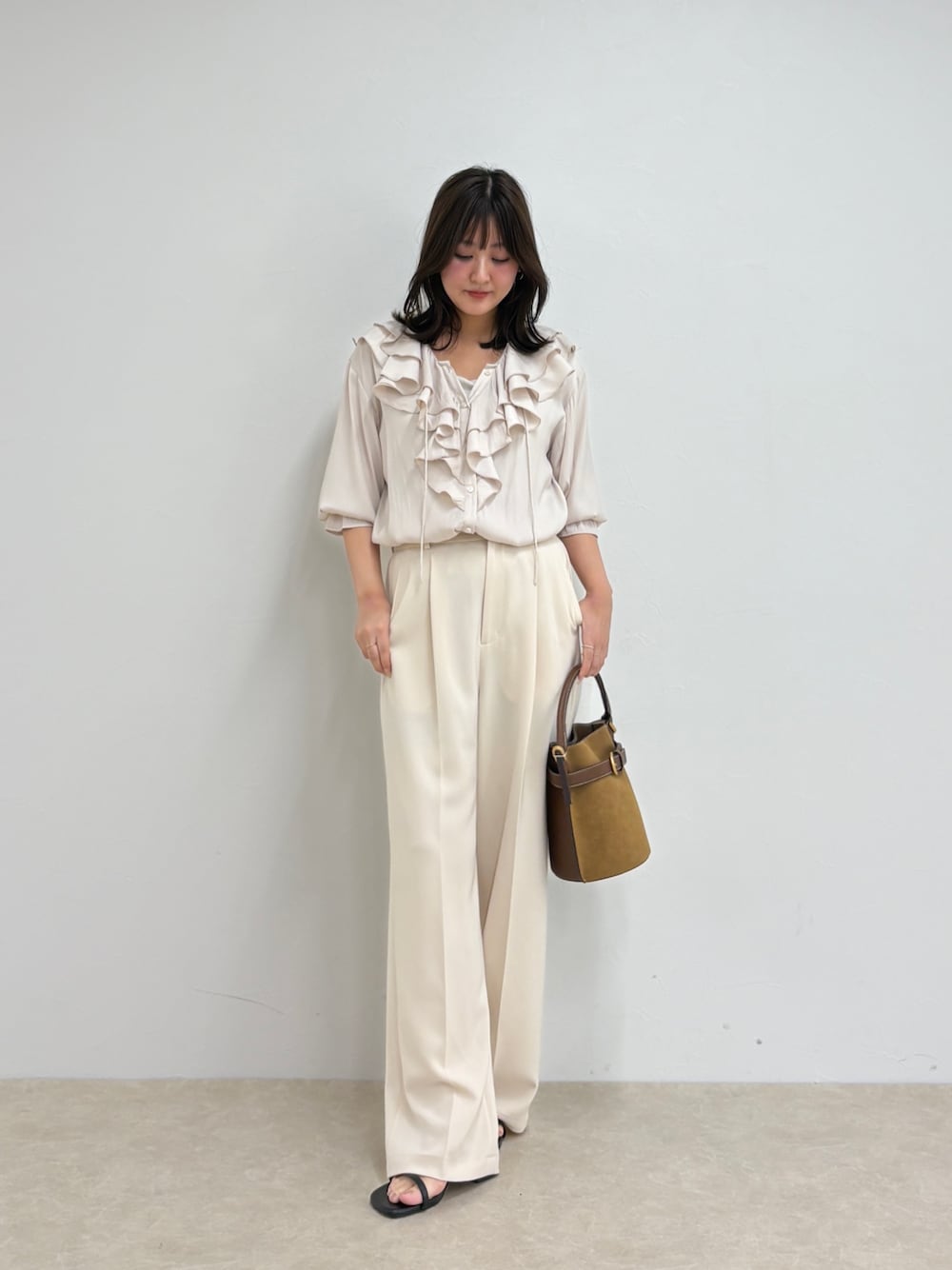 ホワイト系のシャツ/ブラウス、ホワイト系のスラックス、ブラウン系のショルダーバッグを着用したレディースの夏コーディネートの1枚目の写真