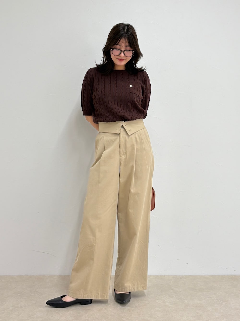 ブラウン系のニット/セーター、ベージュ系のチノパンツ、イエロー系のショルダーバッグを着用したレディースの夏コーディネートの1枚目の写真