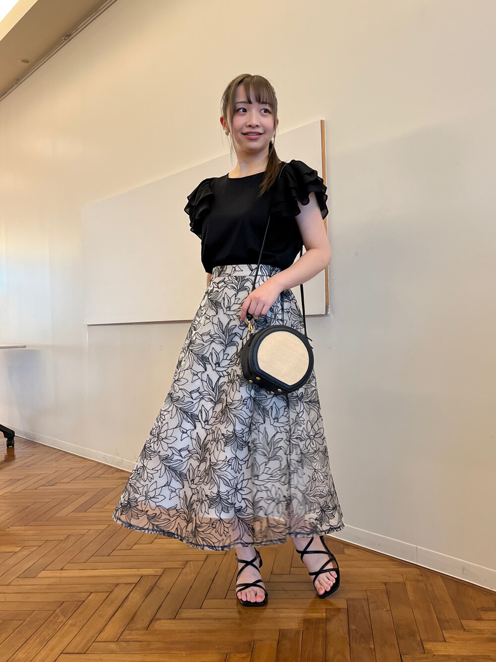 ブラック系のショルダーバッグ、ブラック系のサンダル、ブラック系のスカートを着用したレディースの春コーディネートの1枚目の写真