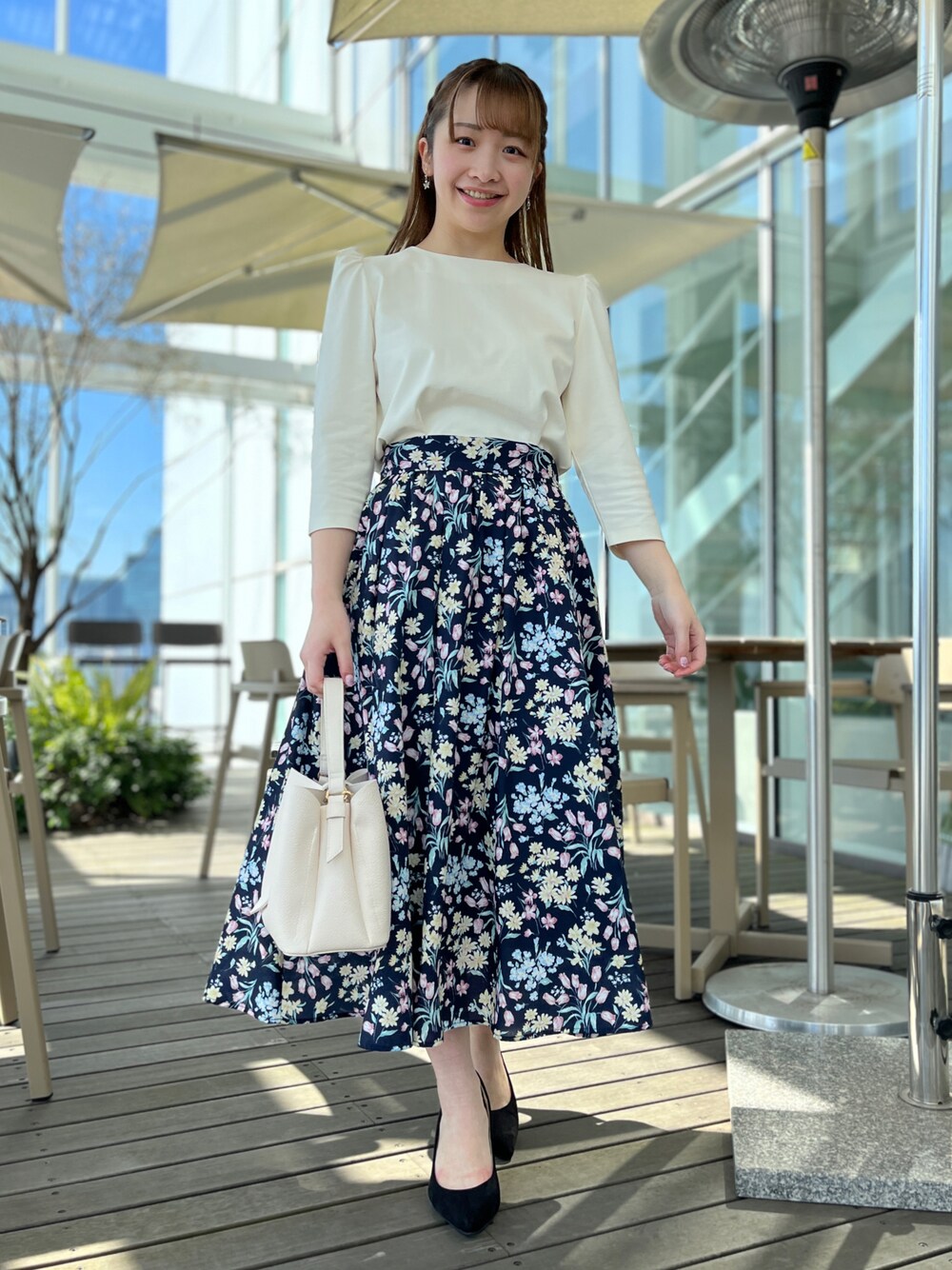 ホワイト系のTシャツ/カットソー、ブルー系のスカート、ブラック系のパンプスを着用したレディースの春コーディネートの1枚目の写真