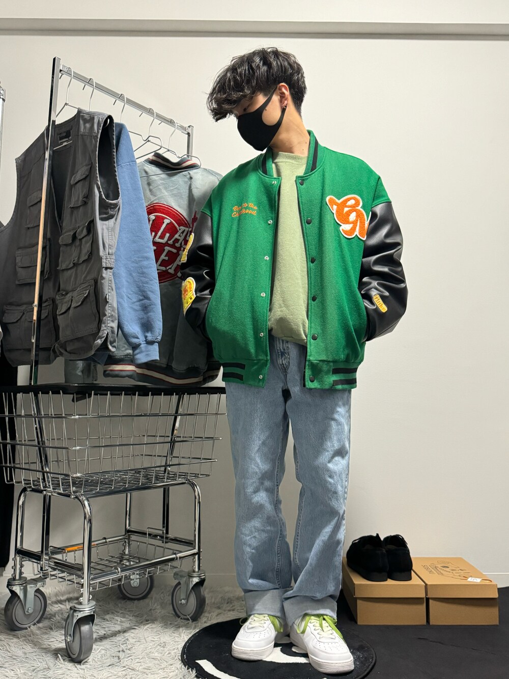 ブルー系のデニムパンツ、ホワイト系のスニーカー、グリーン系のタンクトップを着用したメンズの冬コーディネートの1枚目の写真