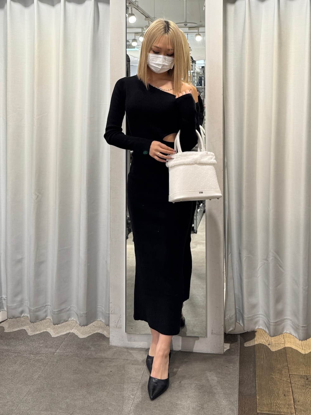 ブラック系のワンピース、ホワイト系のショルダーバッグ、ブラック系のパンプスを着用したレディースの冬コーディネートの1枚目の写真