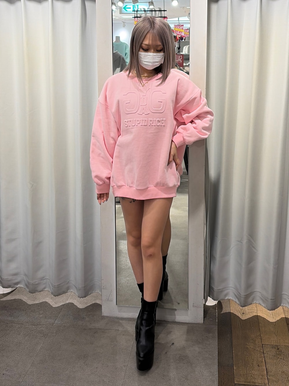 ピンク系のスウェット、ブラック系のブーツを着用したレディースの冬コーディネートの1枚目の写真