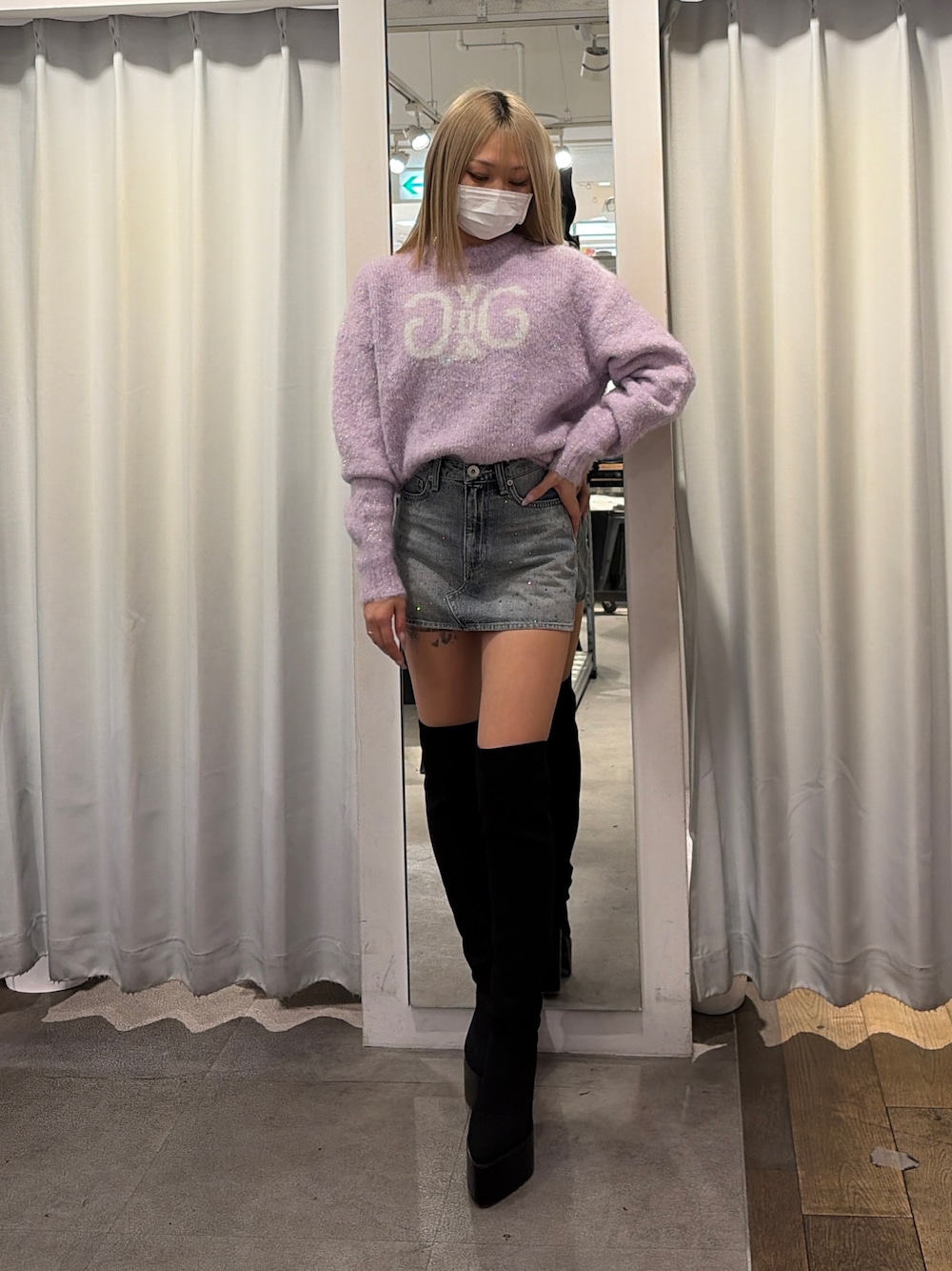 パープル系のニット/セーター、ブルー系のデニムスカート、ブラック系のブーツを着用したレディースの冬コーディネートの1枚目の写真