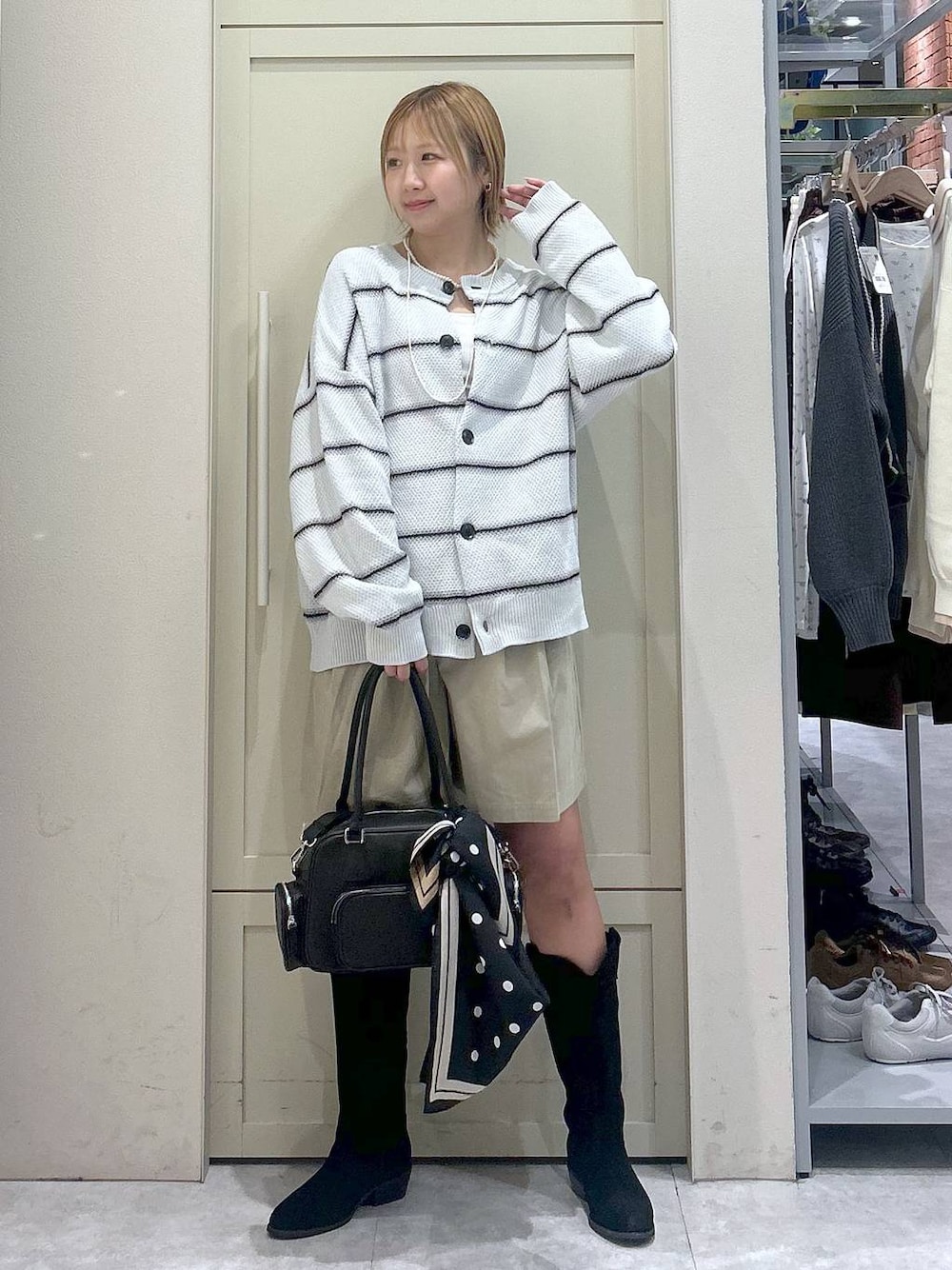 ホワイト系のキャミソール、ブラック系のブーツ、ブラック系のボストンバッグを着用したレディースの春コーディネートの1枚目の写真