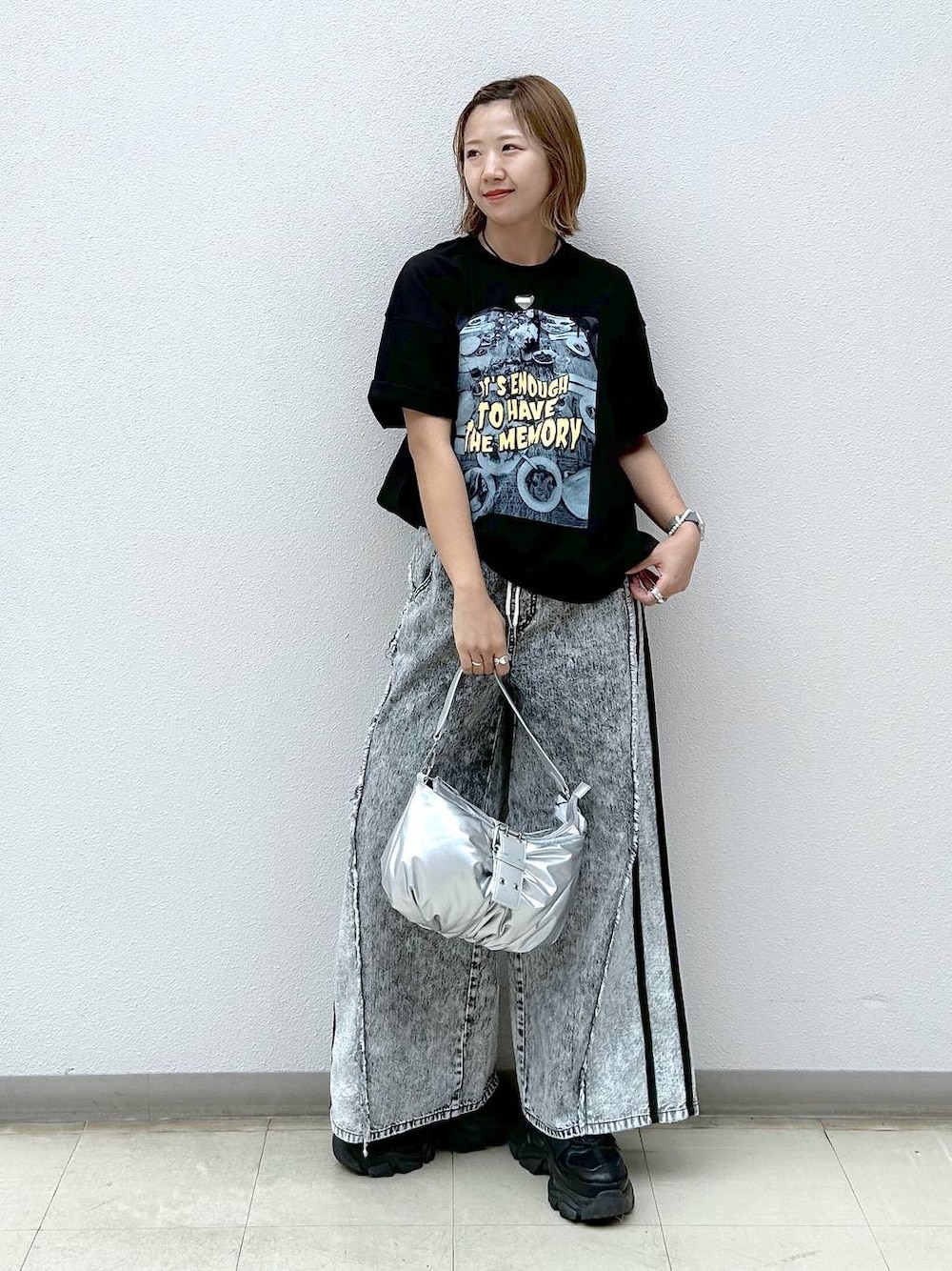 ブラック系のスニーカー、グレー系のデニムパンツ、シルバー系のショルダーバッグを着用したレディースの夏コーディネートの1枚目の写真