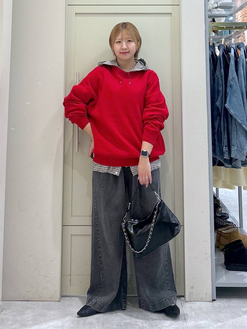 ブラック系のデニムパンツ、レッド系のニット/セーター、ブラック系のショルダーバッグを着用したレディースの春コーディネートの1枚目の写真