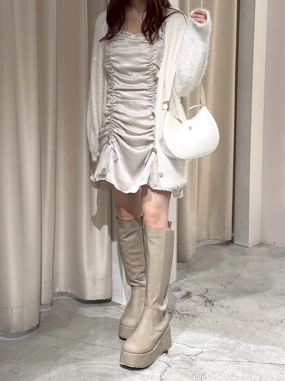 ホワイト系のカーディガン/ボレロ、ベージュ系のブーツ、ホワイト系のショルダーバッグを着用したレディースの秋コーディネートの1枚目の写真