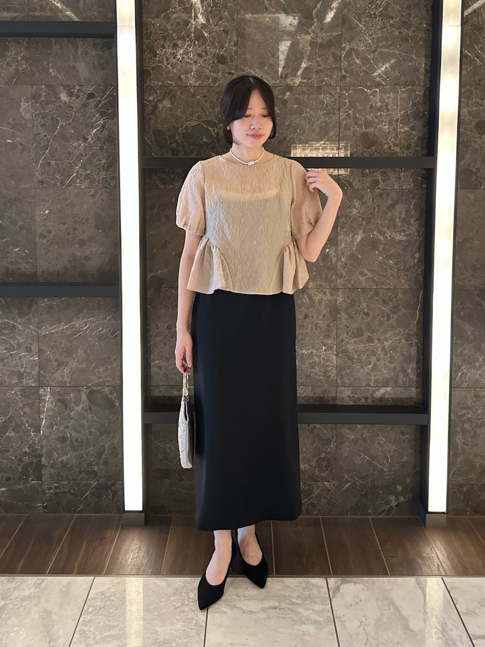 ベージュ系のその他アウター、ブラック系のパンプス、シルバー系のハンドバッグを着用したレディースの秋コーディネートの1枚目の写真