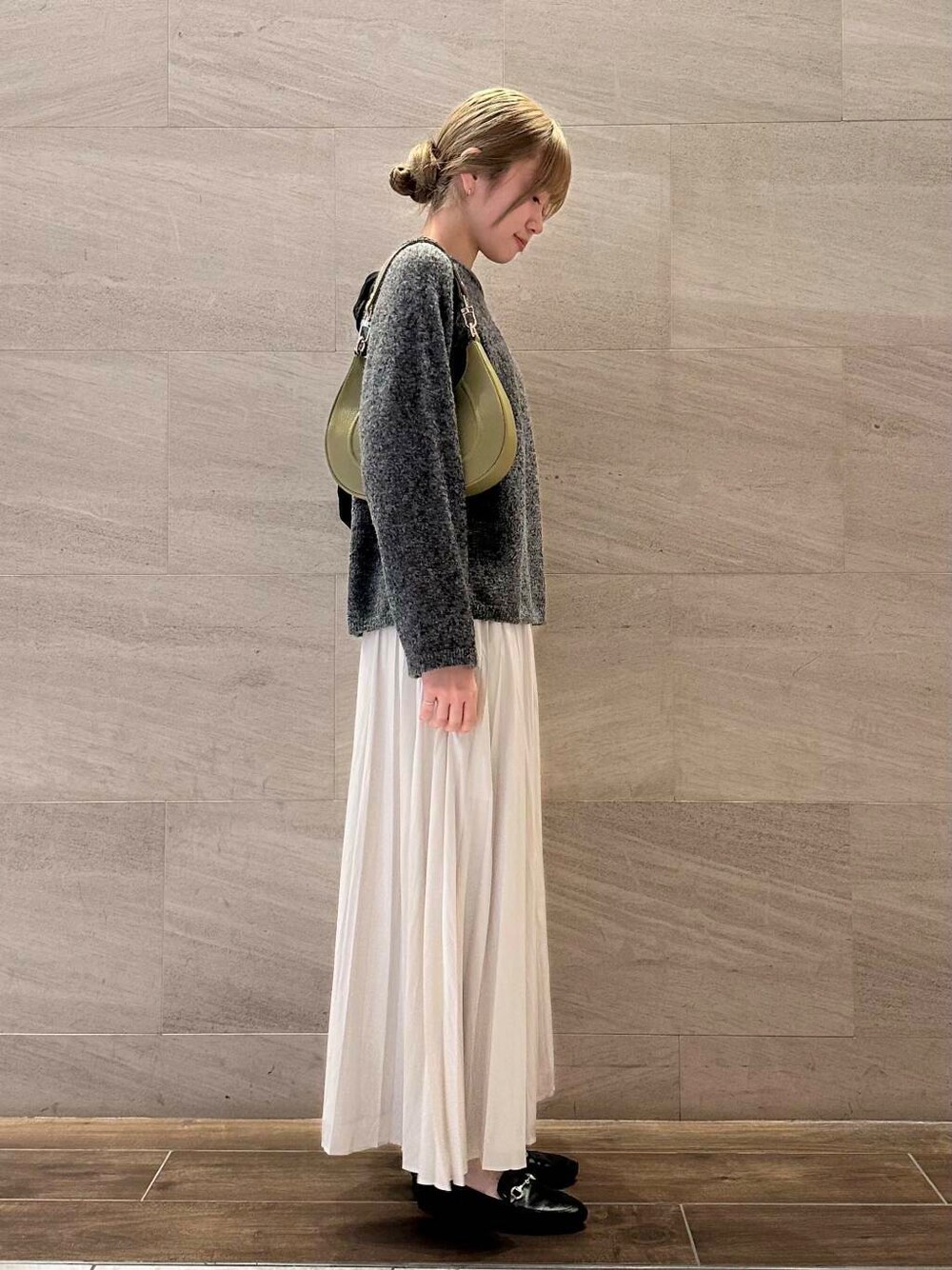 グリーン系のショルダーバッグ、ホワイト系のスカート、グレー系のニット/セーターを着用したレディースの冬コーディネートの1枚目の写真