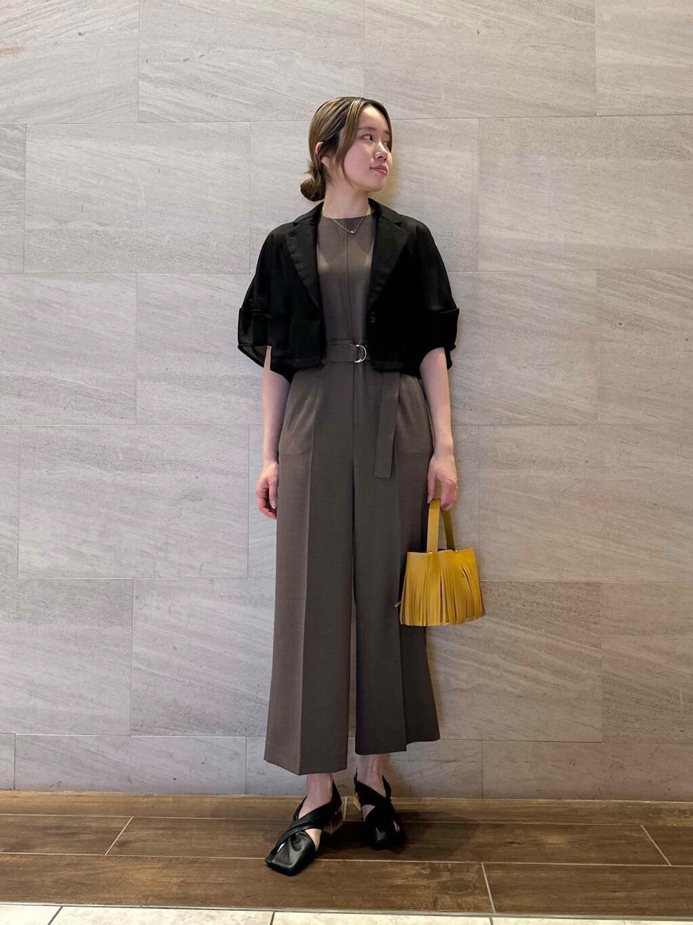 イエロー系のハンドバッグ、ブラック系のその他アウター、ブラウン系のサロペット/オーバーオールを着用したレディースの春コーディネートの1枚目の写真