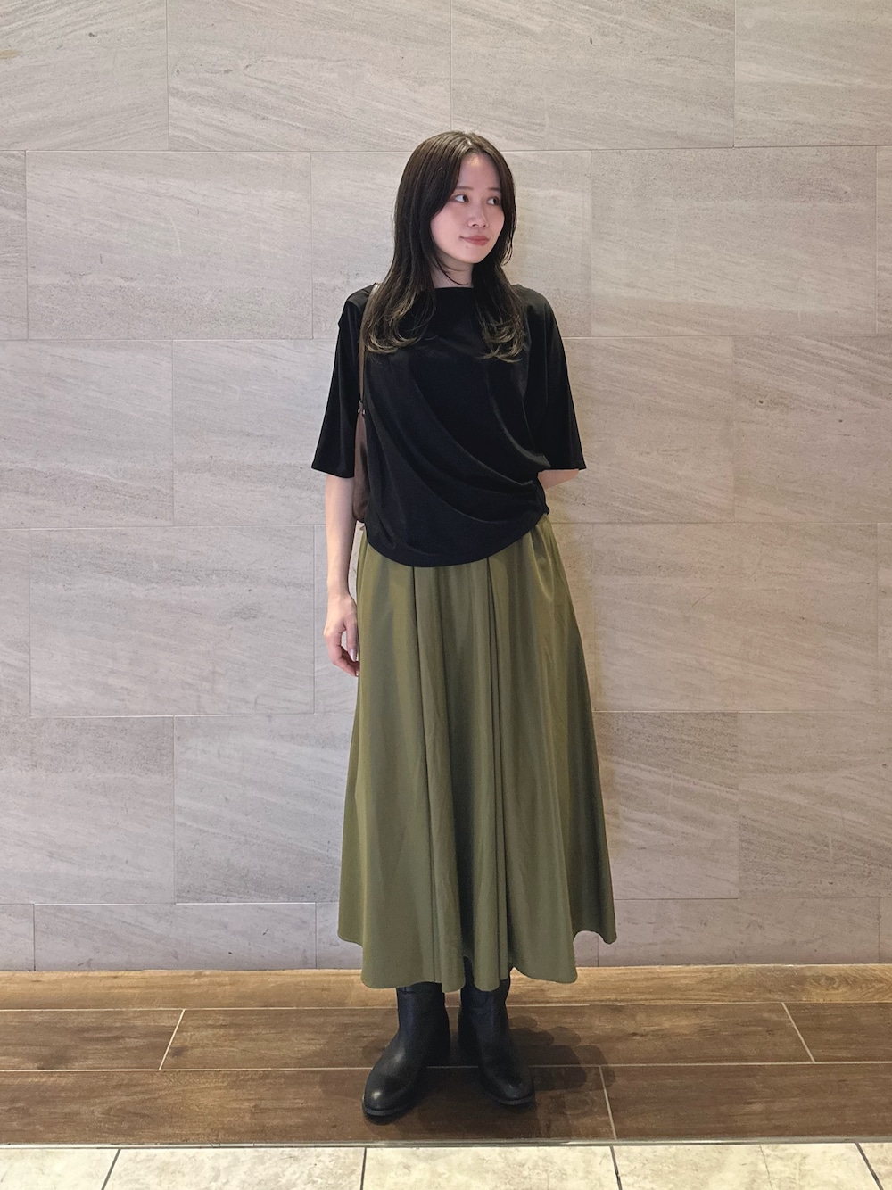 ブラック系のTシャツ/カットソー、グリーン系のスカート、ブラック系のブーツを着用したレディースの秋コーディネートの1枚目の写真