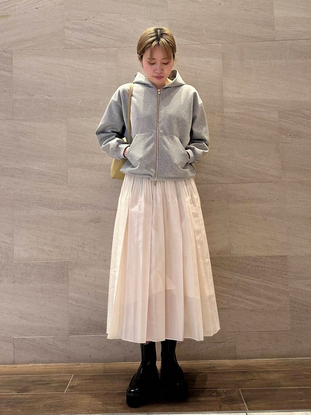 グレー系のブルゾン、ホワイト系のスカート、ベージュ系のショルダーバッグを着用したレディースの冬コーディネートの1枚目の写真