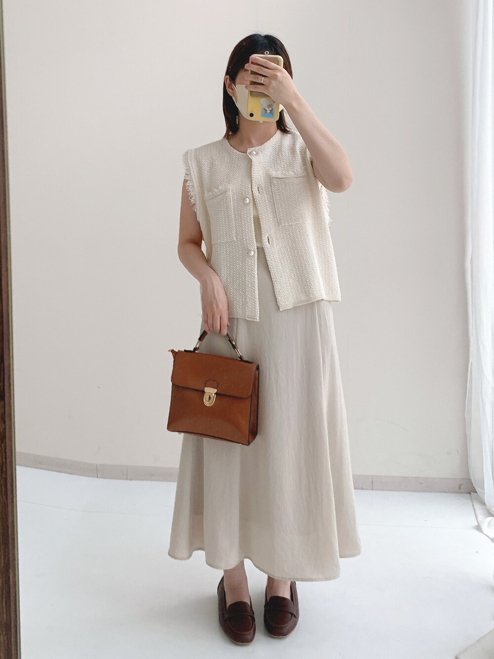 ホワイト系のベスト、ベージュ系のスカートを着用したレディースの夏コーディネートの1枚目の写真