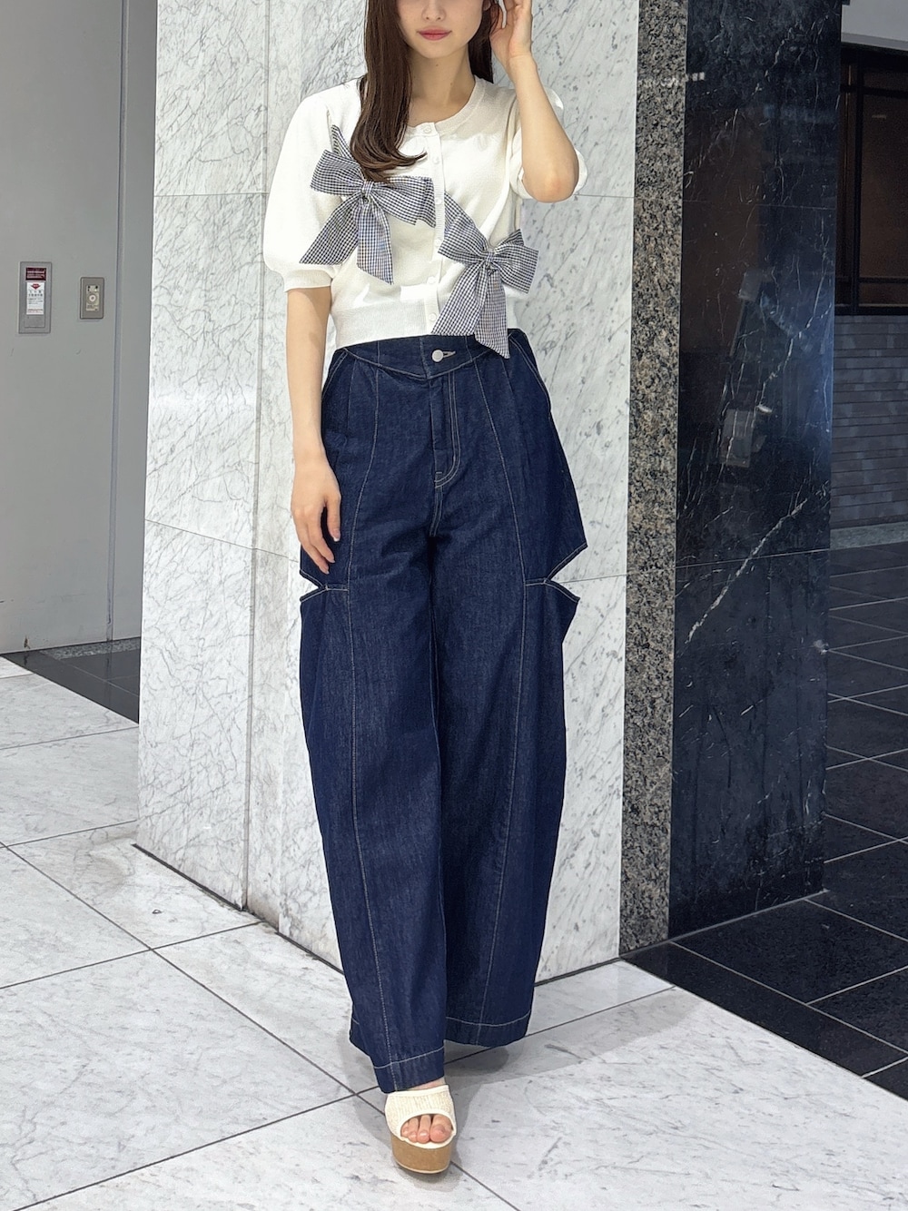 ブルー系のデニムパンツ、ホワイト系のサンダル、ホワイト系のニット/セーターを着用したレディースの春コーディネートの1枚目の写真