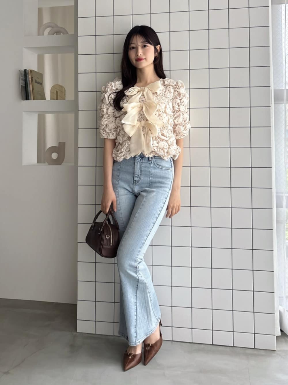 ブラウン系のハンドバッグ、ブルー系のデニムパンツ、ホワイト系のシャツ/ブラウスを着用したレディースの夏コーディネートの1枚目の写真