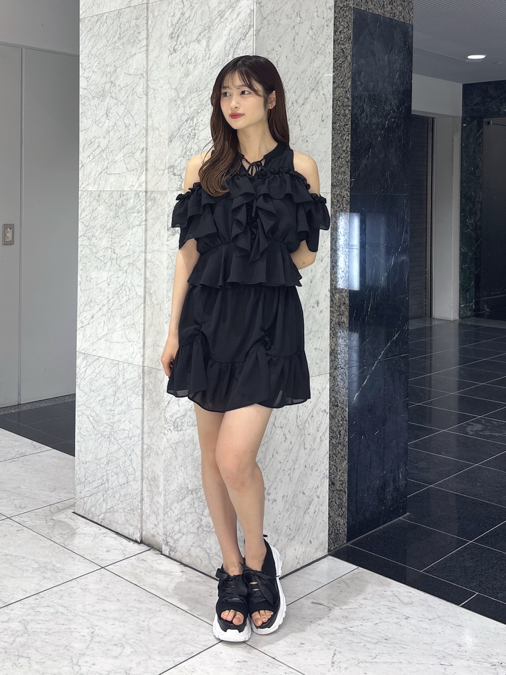 ブラック系のスカート、ブラック系のシャツ/ブラウス、ブラック系のサンダルを着用したレディースの春コーディネートの1枚目の写真