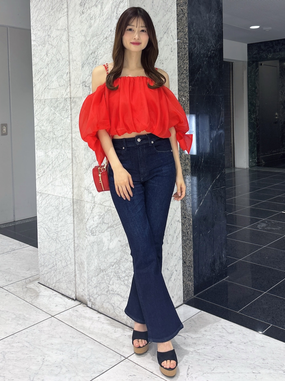 ブルー系のデニムパンツ、レッド系のシャツ/ブラウス、レッド系のショルダーバッグを着用したレディースの春コーディネートの1枚目の写真