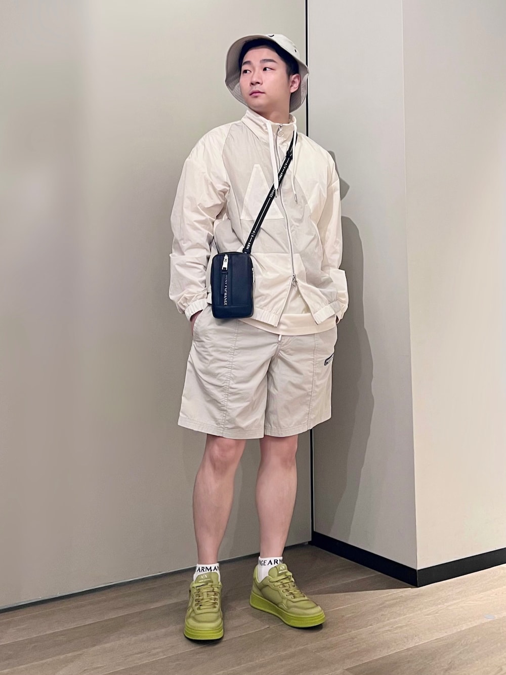 イエロー系のスニーカー、ホワイト系のTシャツ/カットソー、ベージュ系のナイロンジャケットを着用したメンズの春コーディネートの1枚目の写真