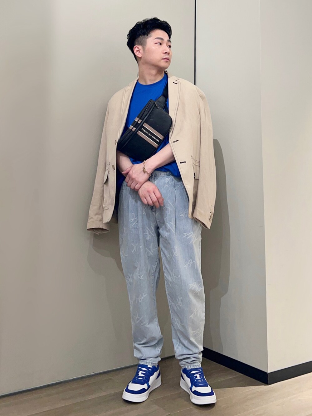 ブルー系のスニーカー、ブルー系のデニムパンツ、ブラック系のボディバッグ/ウエストポーチを着用したメンズの春コーディネートの1枚目の写真