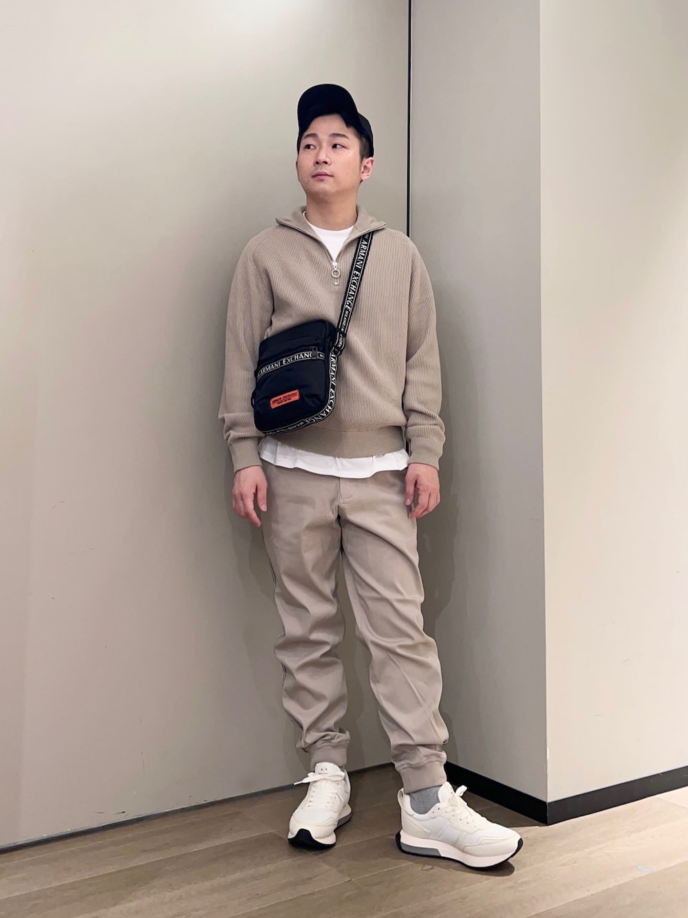 ブラック系のショルダーバッグ、ホワイト系のTシャツ/カットソー、ベージュ系のニット/セーターを着用したメンズの秋コーディネートの1枚目の写真