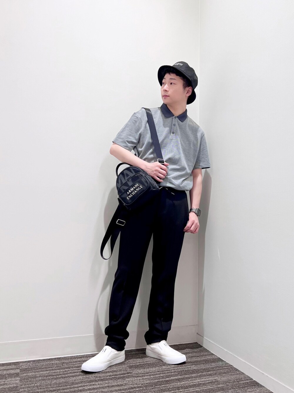 グリーン系のポロシャツ、ブルー系のスラックス、ホワイト系のスニーカーを着用したメンズの夏コーディネートの1枚目の写真