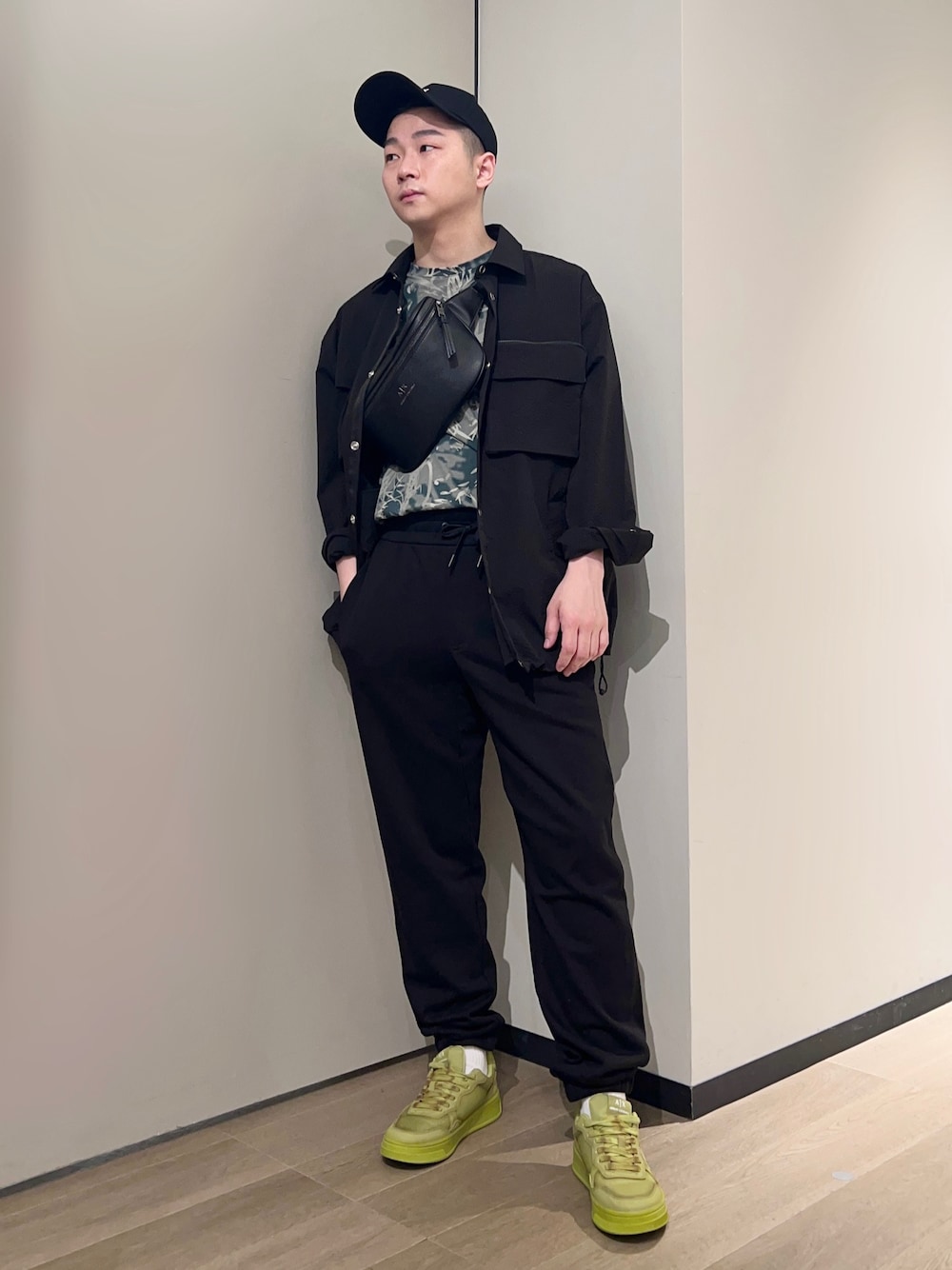 イエロー系のスニーカー、ブラック系のスウェットパンツ、グリーン系のTシャツ/カットソーを着用したメンズの春コーディネートの1枚目の写真