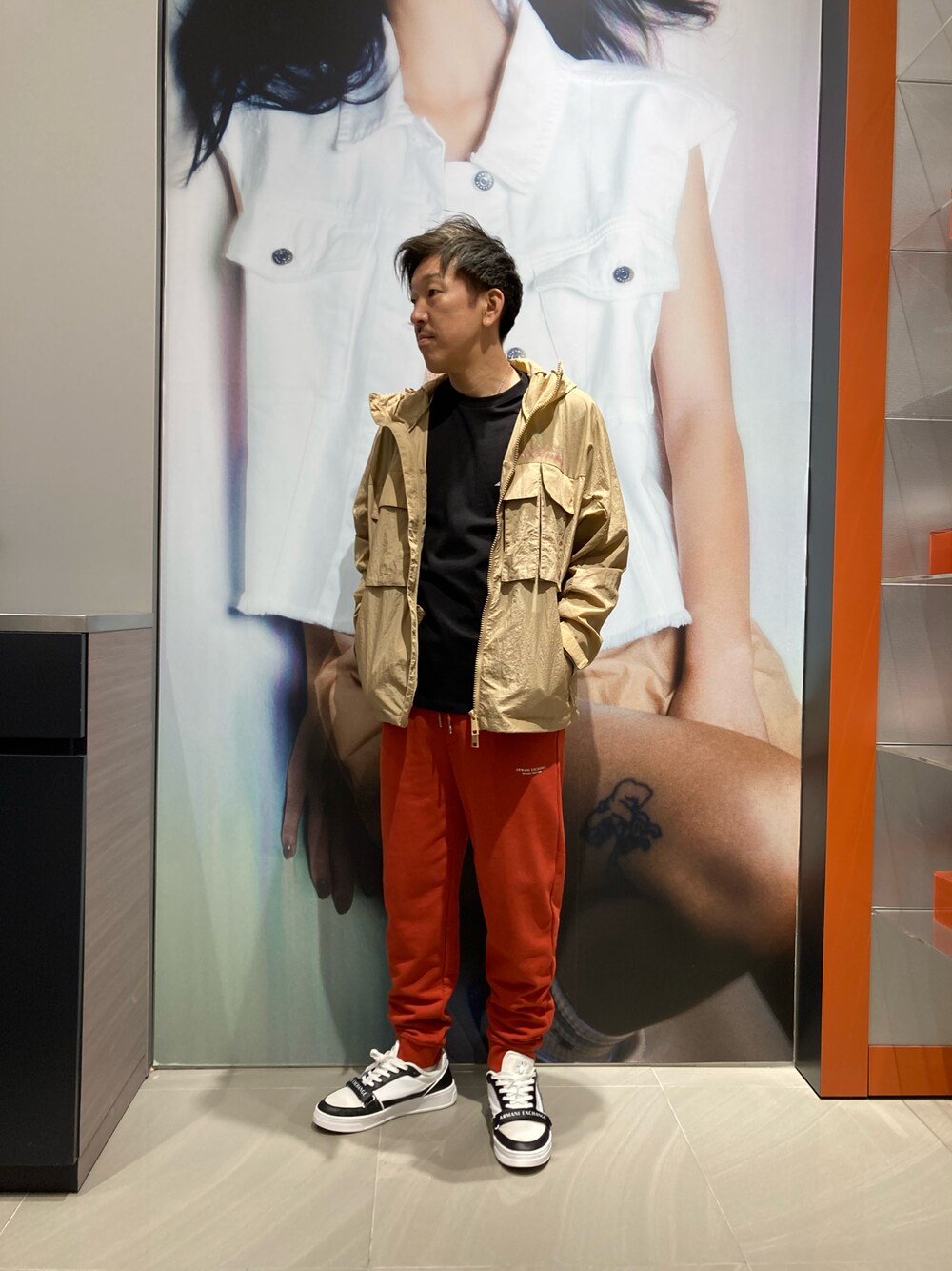 ホワイト系のスニーカー、ベージュ系のナイロンジャケット、レッド系のスウェットパンツを着用したメンズの春コーディネートの1枚目の写真
