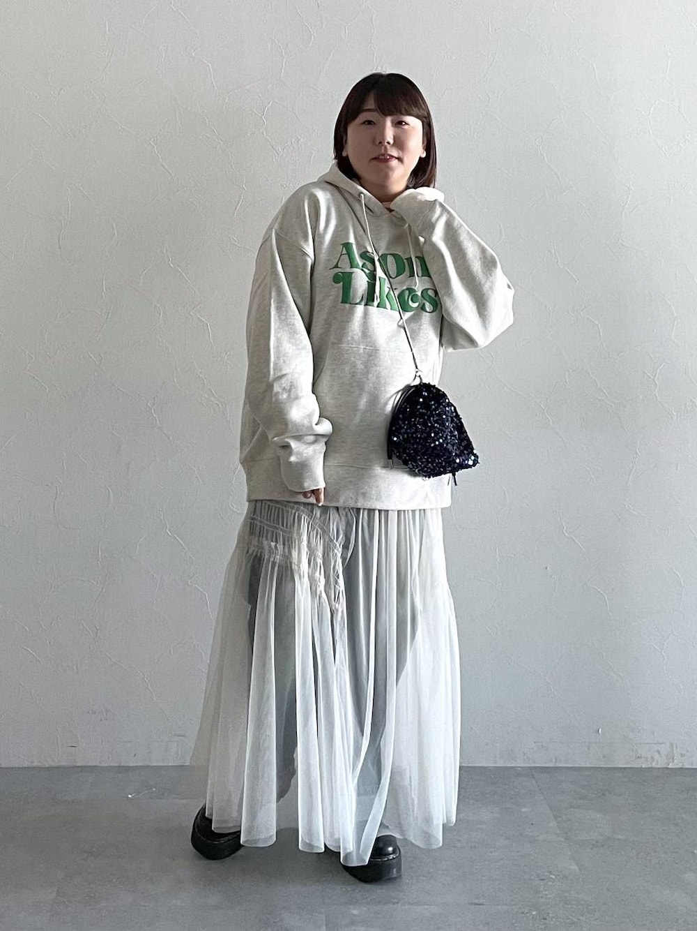 ブルー系のデニムパンツ、ホワイト系のスカート、ブラック系のショルダーバッグを着用したレディースの秋コーディネートの1枚目の写真