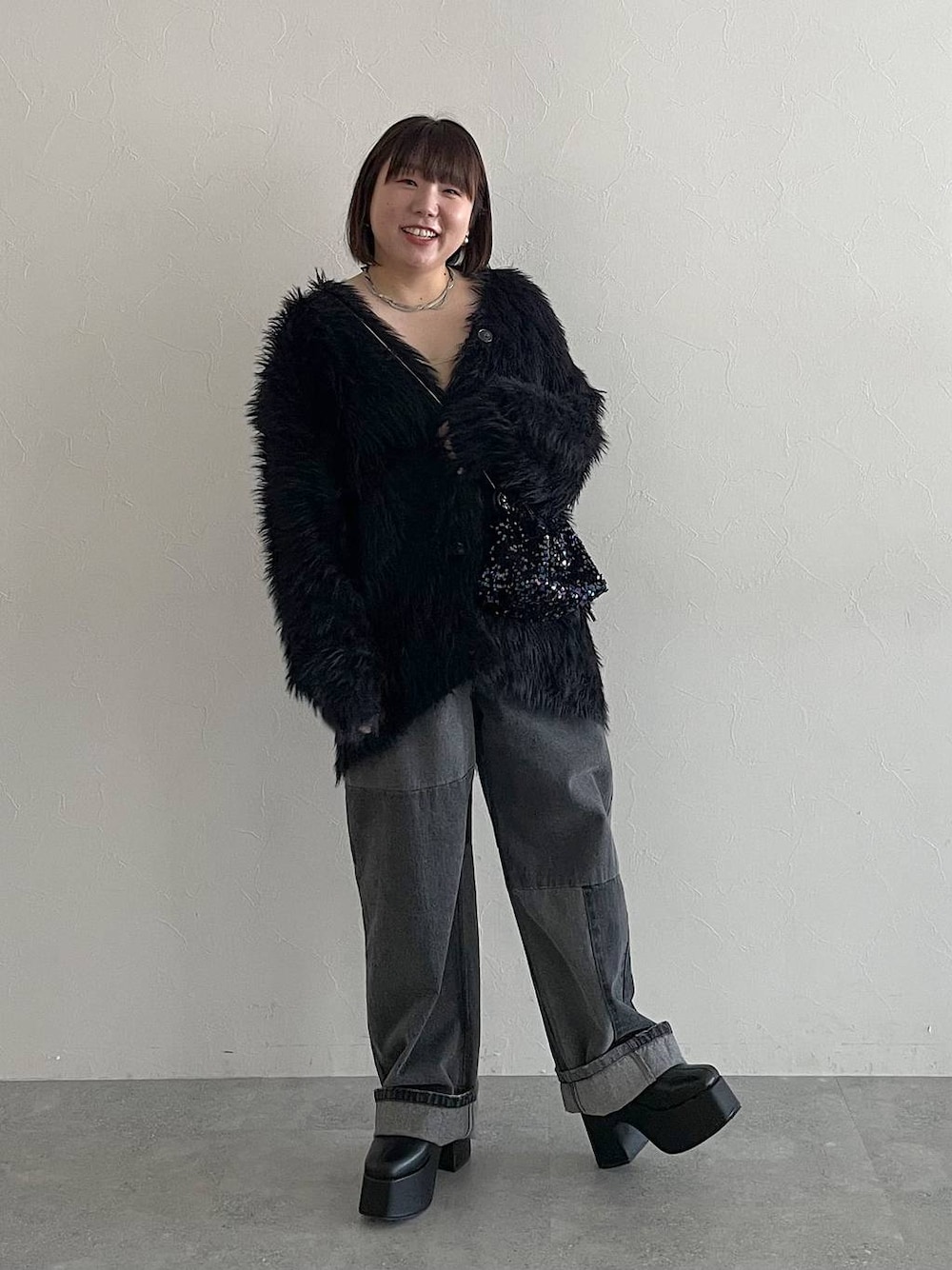 ブラック系のデニムパンツ、ブラック系のカーディガン/ボレロ、ブラック系のブーツを着用したレディースの秋コーディネートの1枚目の写真