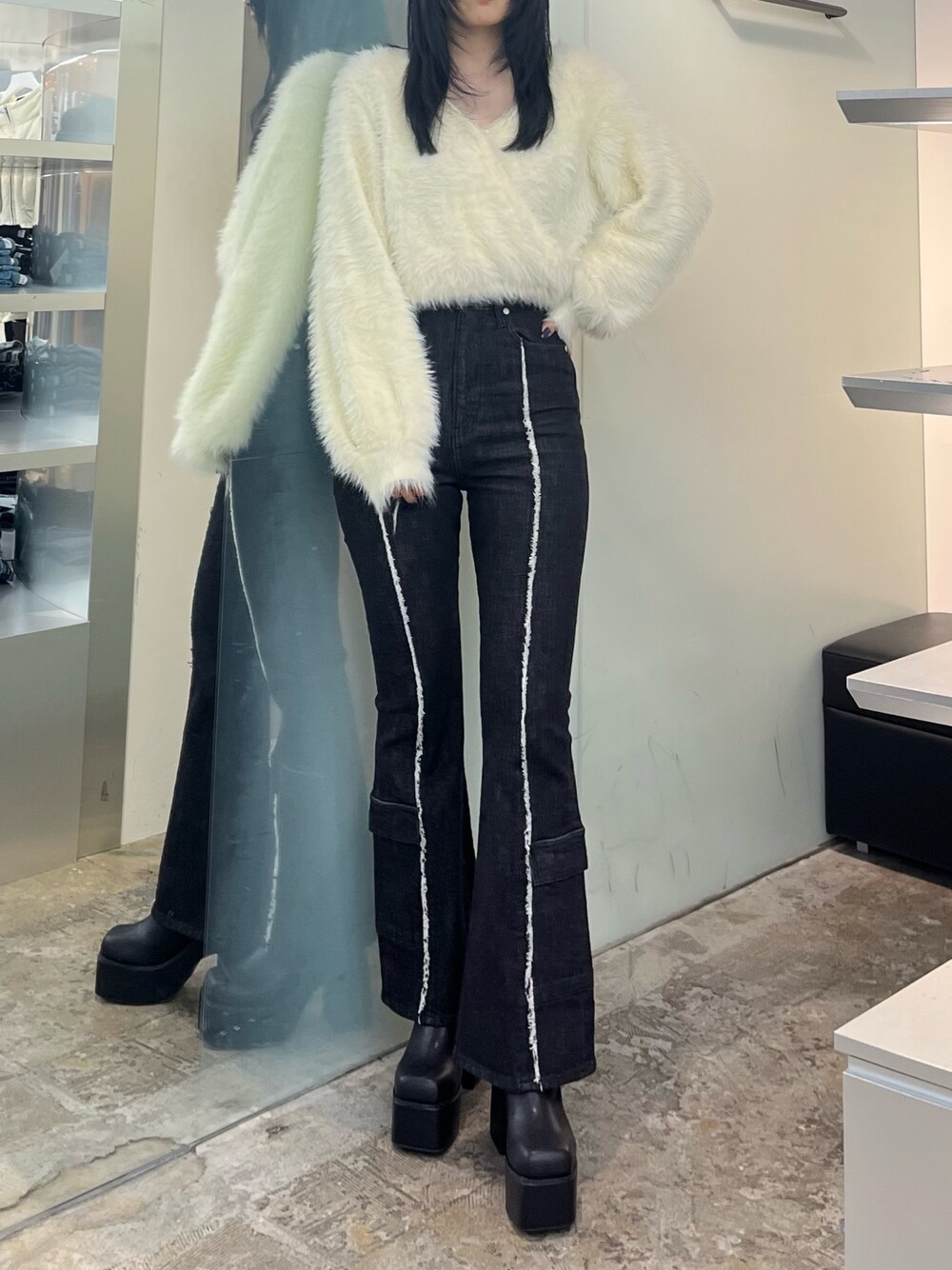 ホワイト系のニット/セーター、ブラック系のデニムパンツ、ブラック系のブーツを着用したレディースの秋コーディネートの1枚目の写真