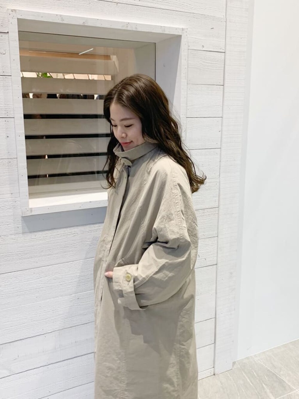 ベージュ系のステンカラーコートを着用したレディースの春コーディネートの1枚目の写真