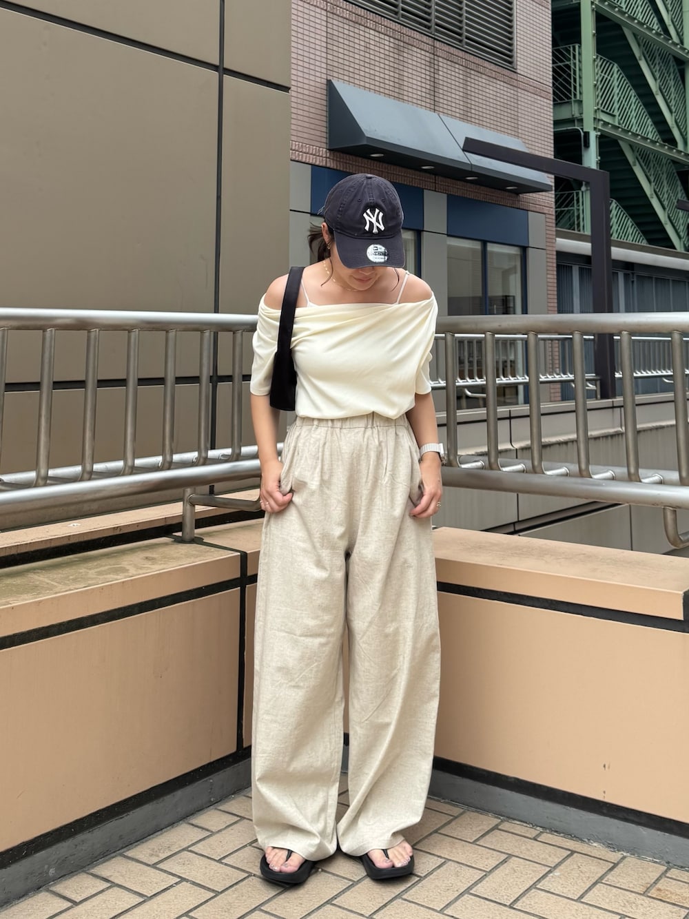 ホワイト系のTシャツ/カットソー、ベージュ系のその他パンツ、ブラック系のハンドバッグを着用したレディースの夏コーディネートの1枚目の写真