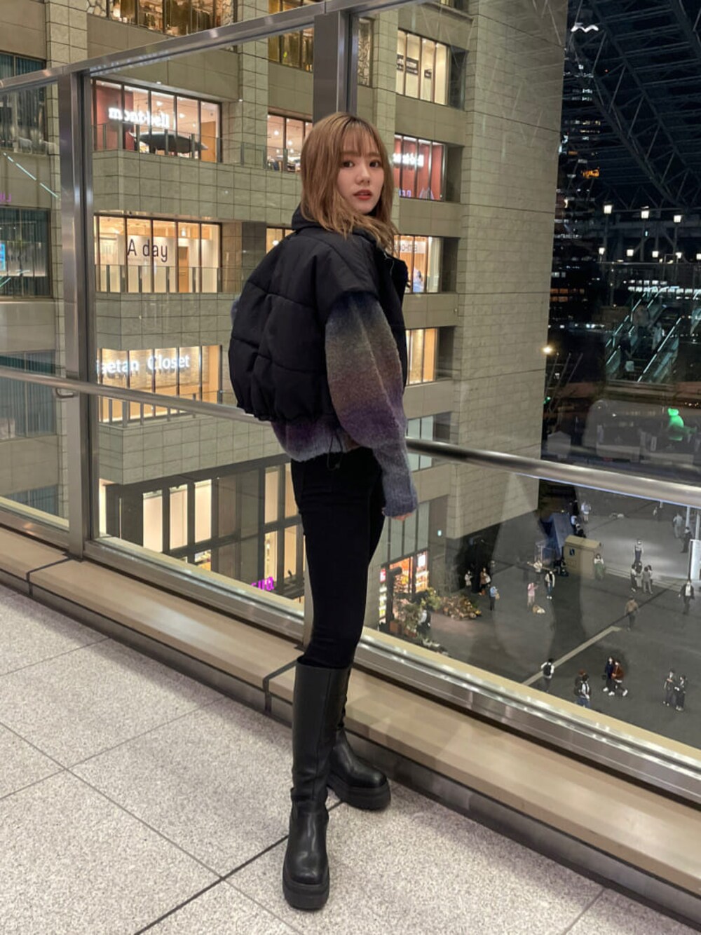 ブラック系のダウンベスト、ブラック系のブーツ、パープル系のニット/セーターを着用したレディースの秋コーディネートの1枚目の写真