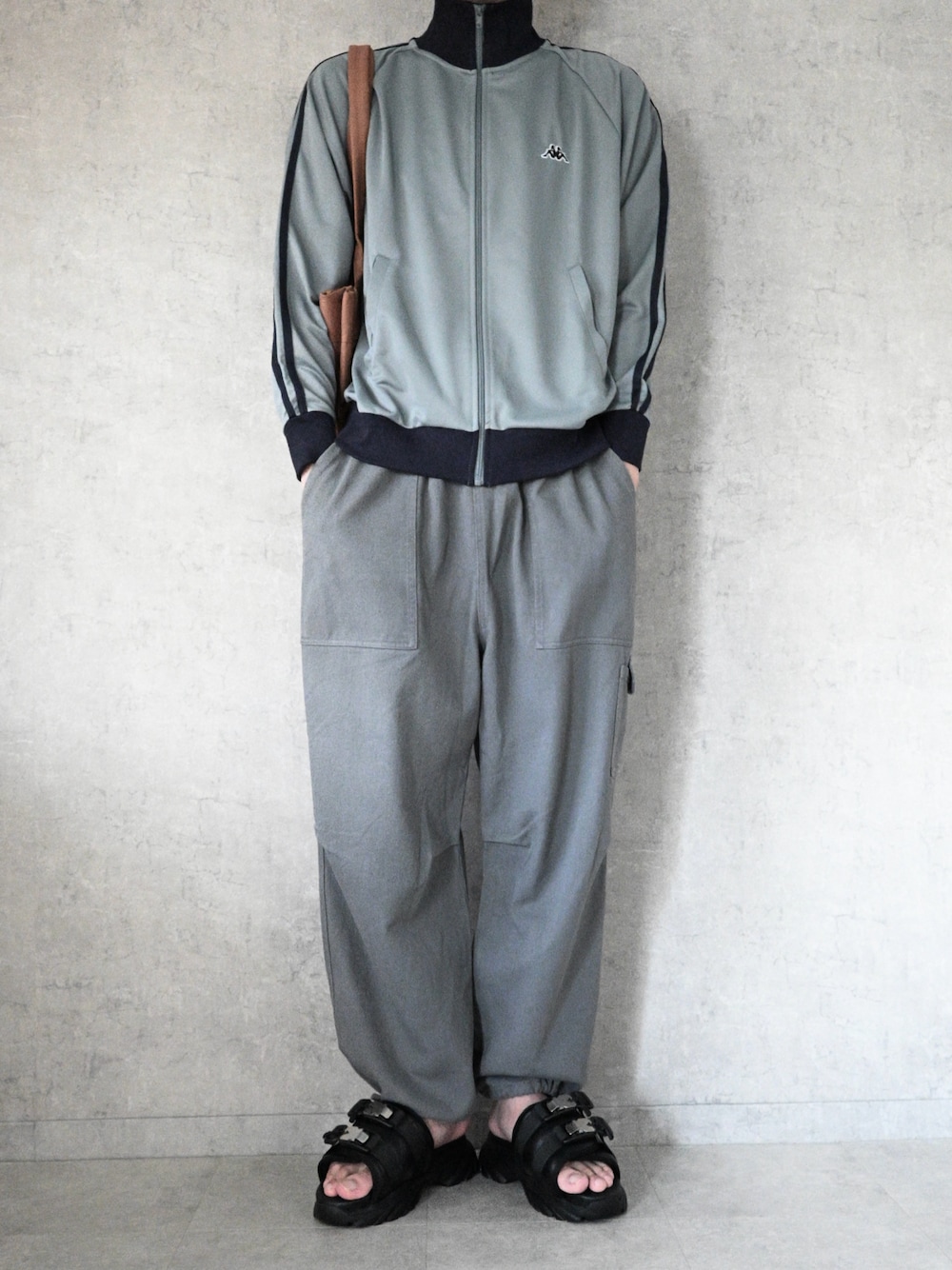 ブルー系のジャージ、グレー系のカーゴパンツ、ブラウン系のトートバッグを着用したメンズの夏コーディネートの1枚目の写真