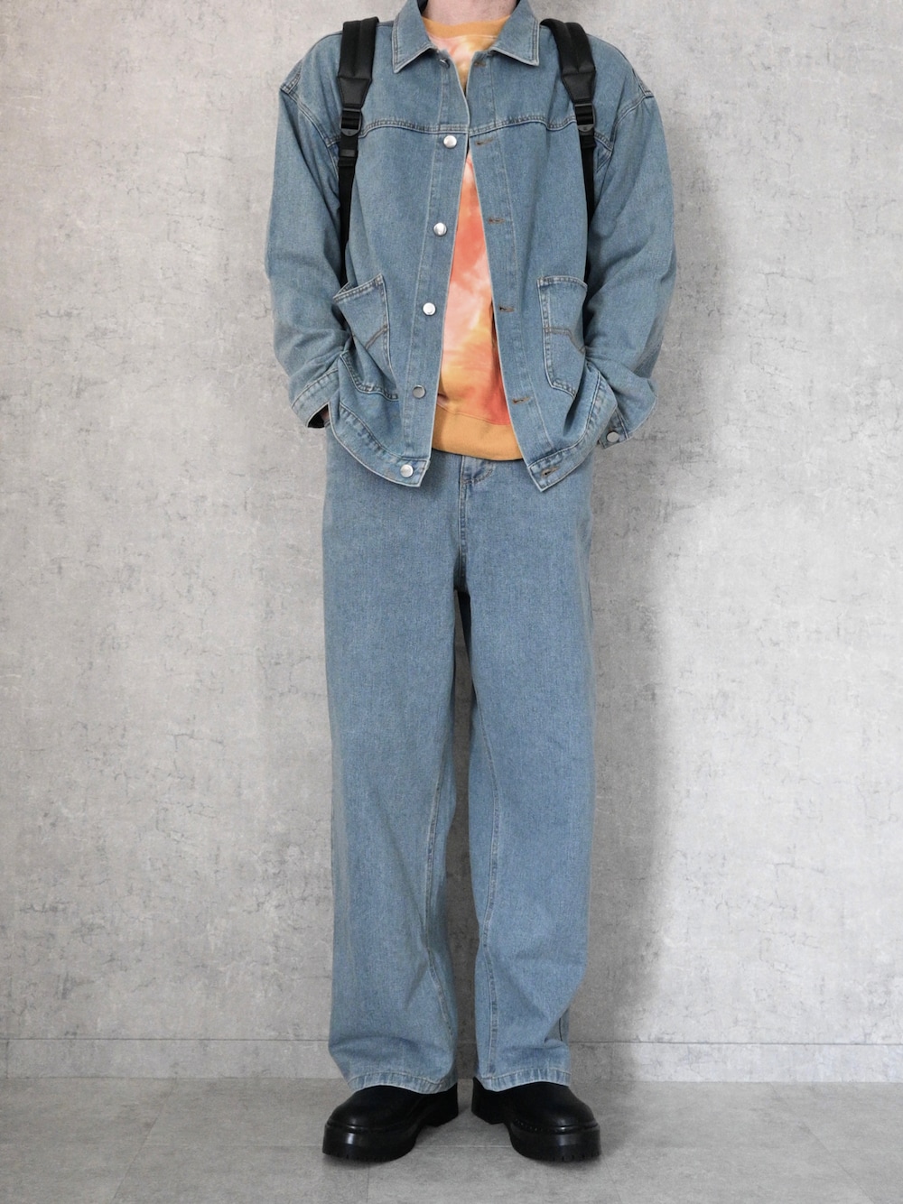 ブルー系のデニムジャケット、ブルー系のデニムパンツ、オレンジ系のスウェットを着用したメンズの冬コーディネートの1枚目の写真