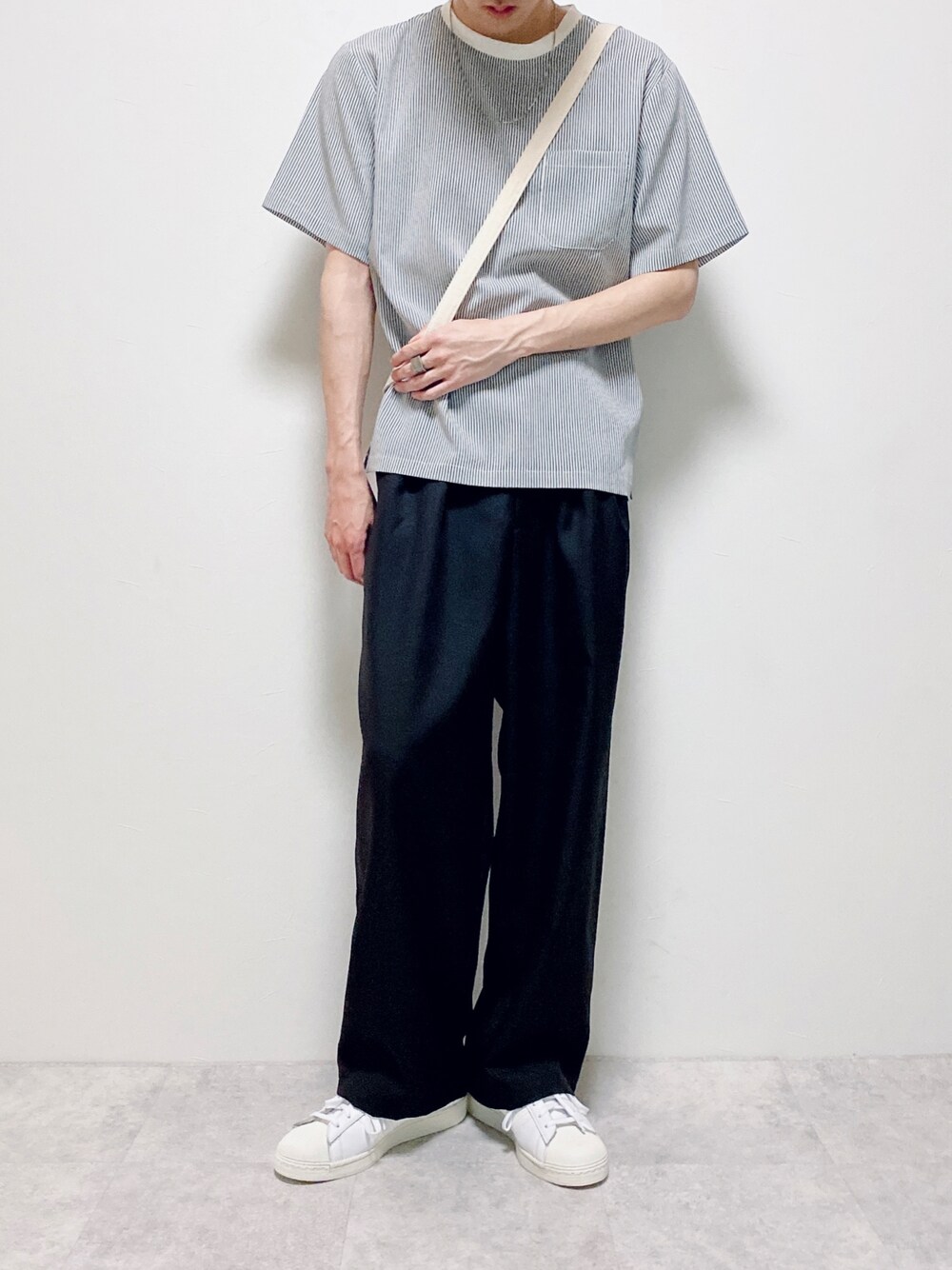 ブルー系のTシャツ/カットソー、ベージュ系のショルダーバッグ、ブラック系のスラックスを着用したメンズの夏コーディネートの1枚目の写真