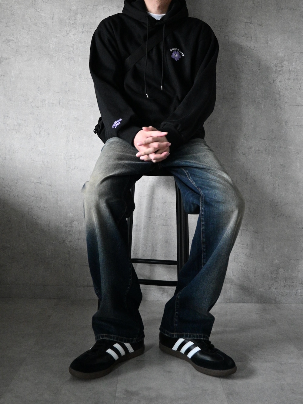 ブラック系のパーカー、ブラック系のスニーカー、ブルー系のデニムパンツを着用したメンズの春コーディネートの1枚目の写真