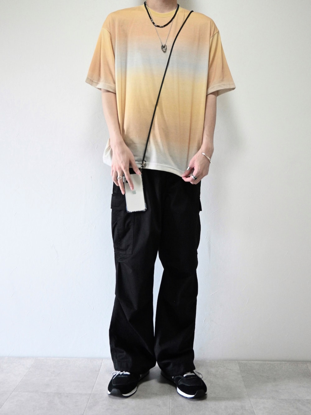 ベージュ系のTシャツ/カットソー、ブラック系のカーゴパンツ、ブラック系のスニーカーを着用したメンズの夏コーディネートの1枚目の写真