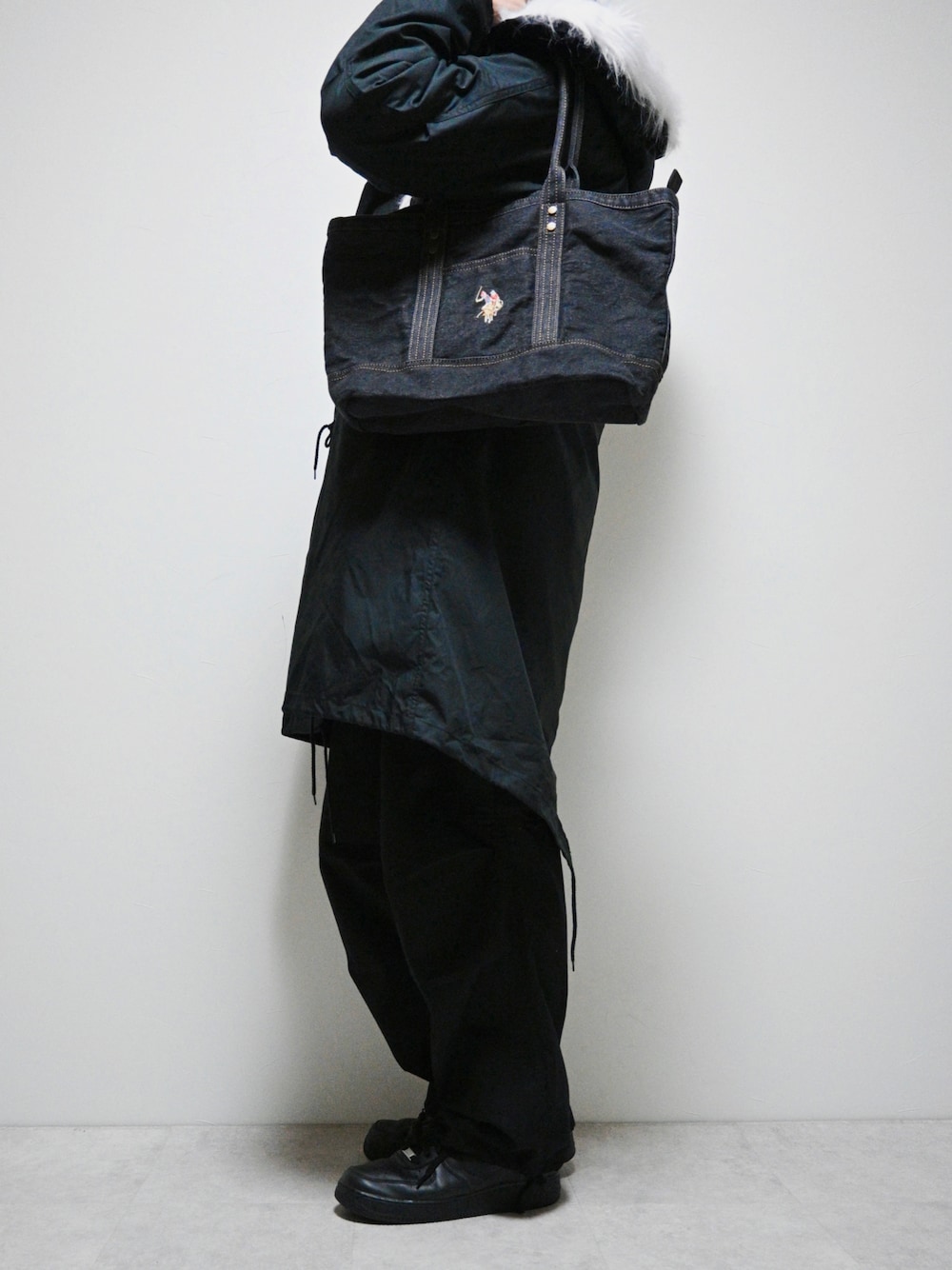 ブラック系のトートバッグ、ブラック系のモッズコート、ブラック系のカーゴパンツを着用したメンズの冬コーディネートの1枚目の写真